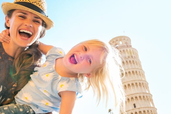 Mother and daughter smiling and standing in front of the Leaning Tower of Pisa, Italy