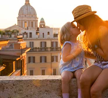 Daughter kissing her Mom, atop a building, in Rome, Italy